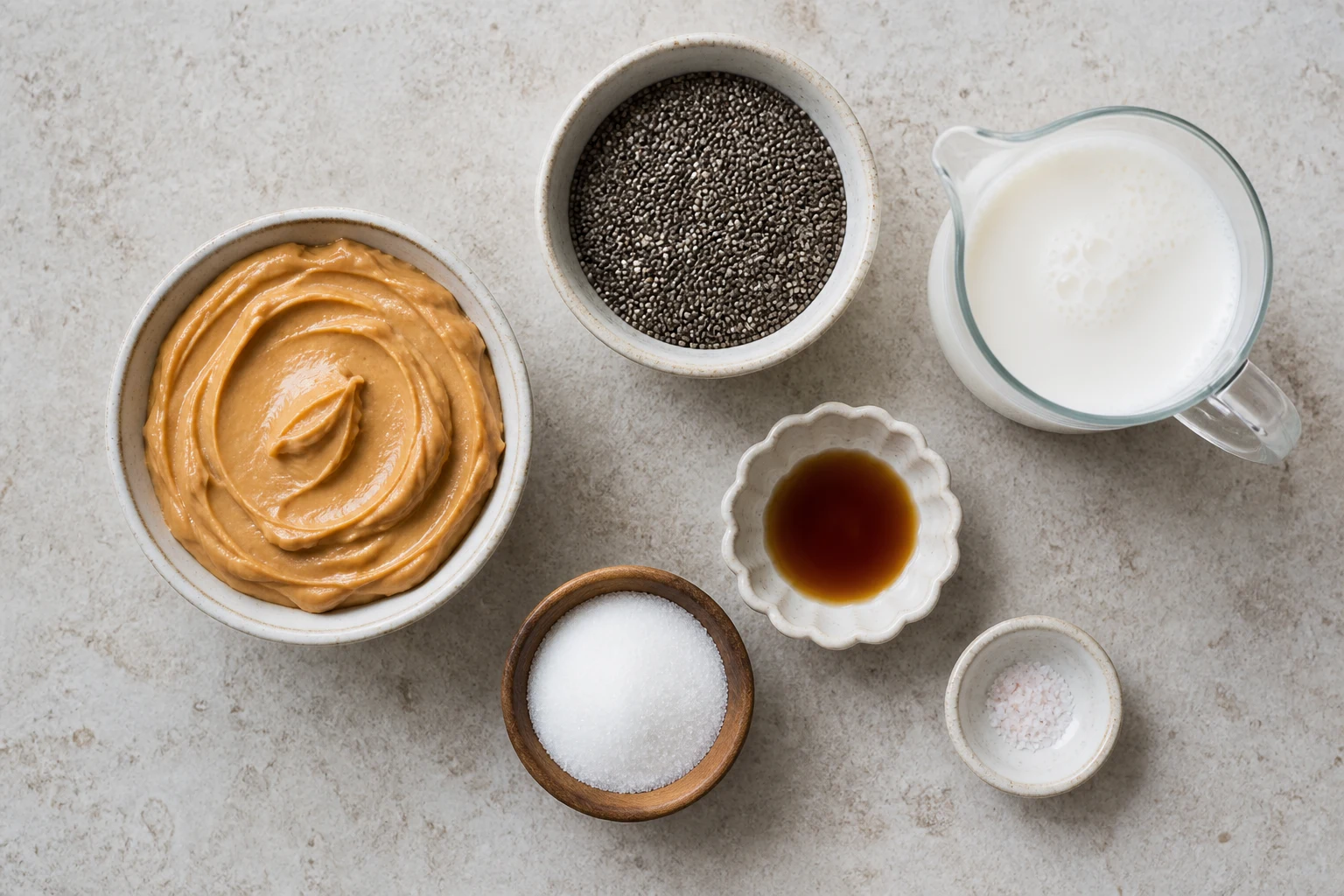 peanut butter ingredients, chia seeds, milk, sweetener, vanilla and salt arranged in a clean flat-lay.