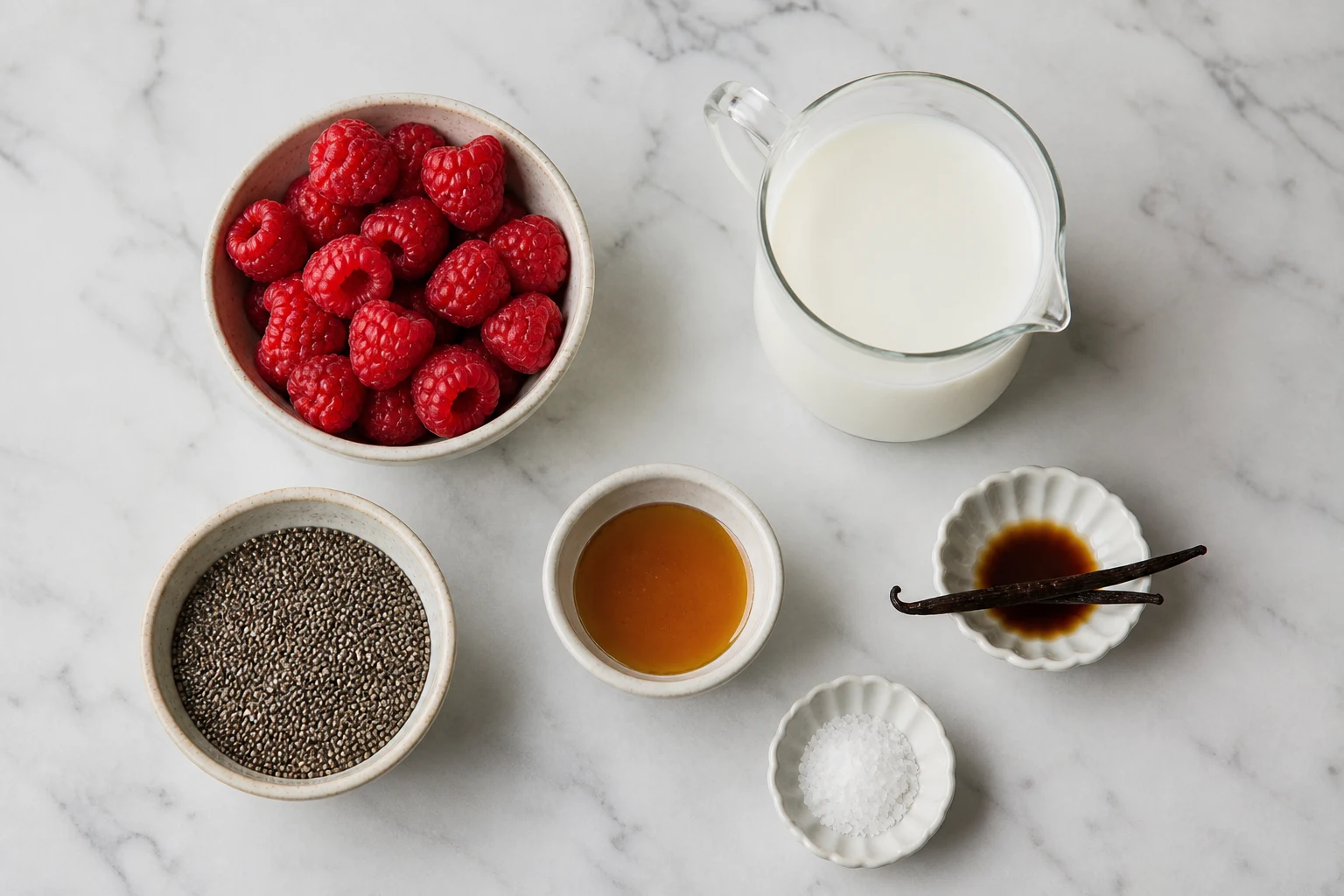 raspberry ingredients, chia seeds, milk, sweetener, vanilla and salt arranged in a clean flat-lay.