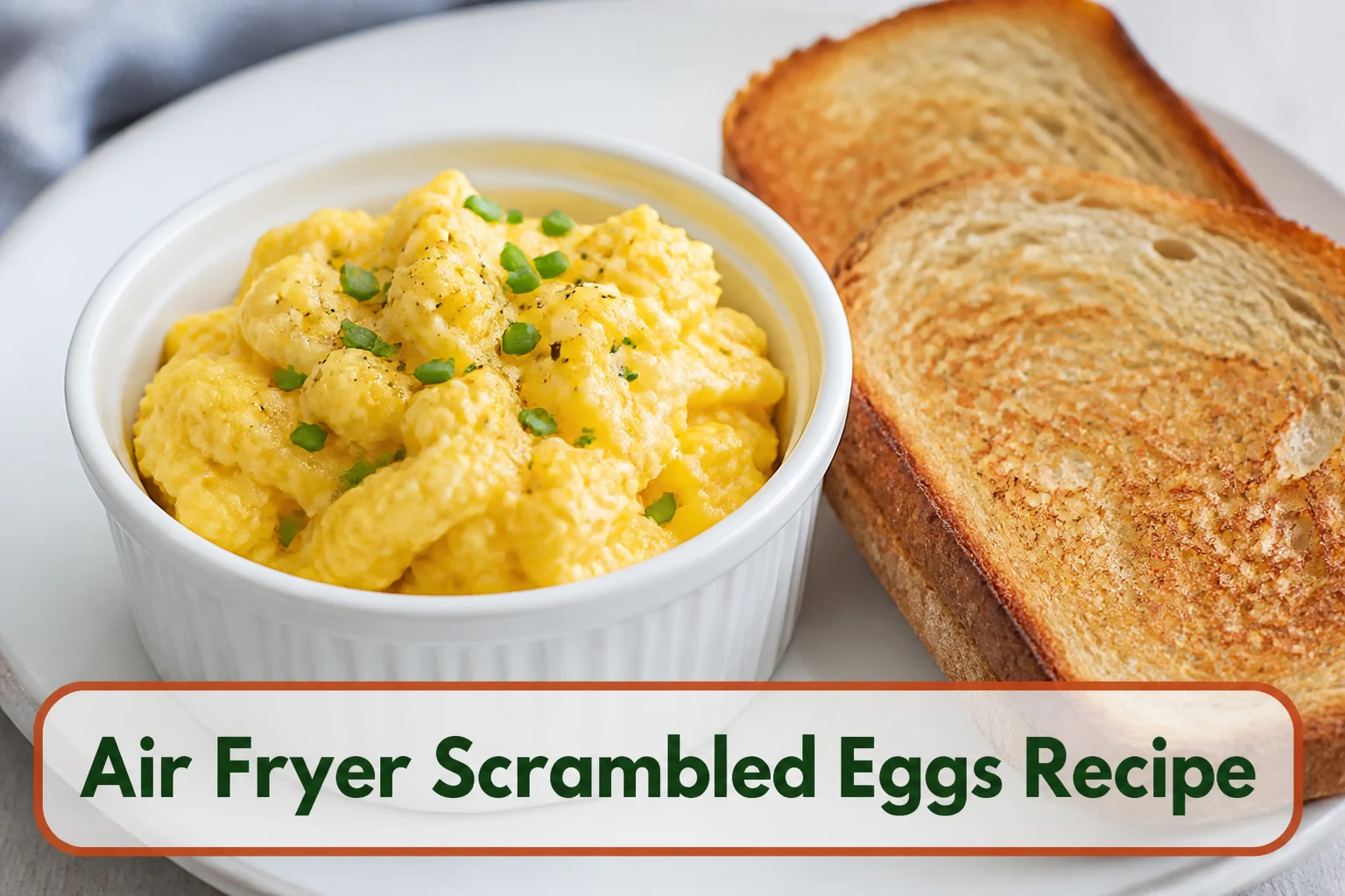 Soft creamy scrambled eggs in a small white ramekin with chives and toast beside it, visible tender curds and natural breakfast light.; title text reads Air Fryer Scrambled Eggs Recipe